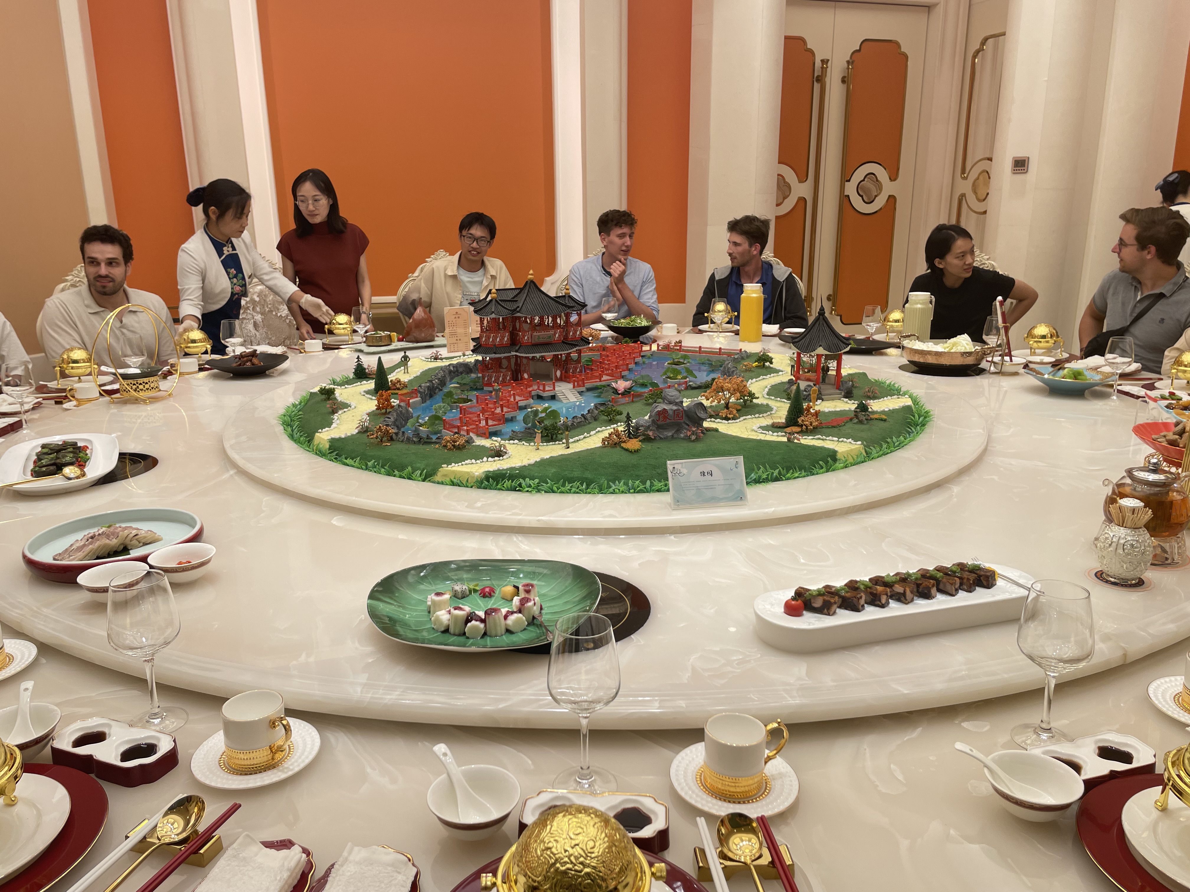 Gro&szlig;es asiatisches Buffet am runden Tisch mit Miniaturstadtmodell in Zentrum.