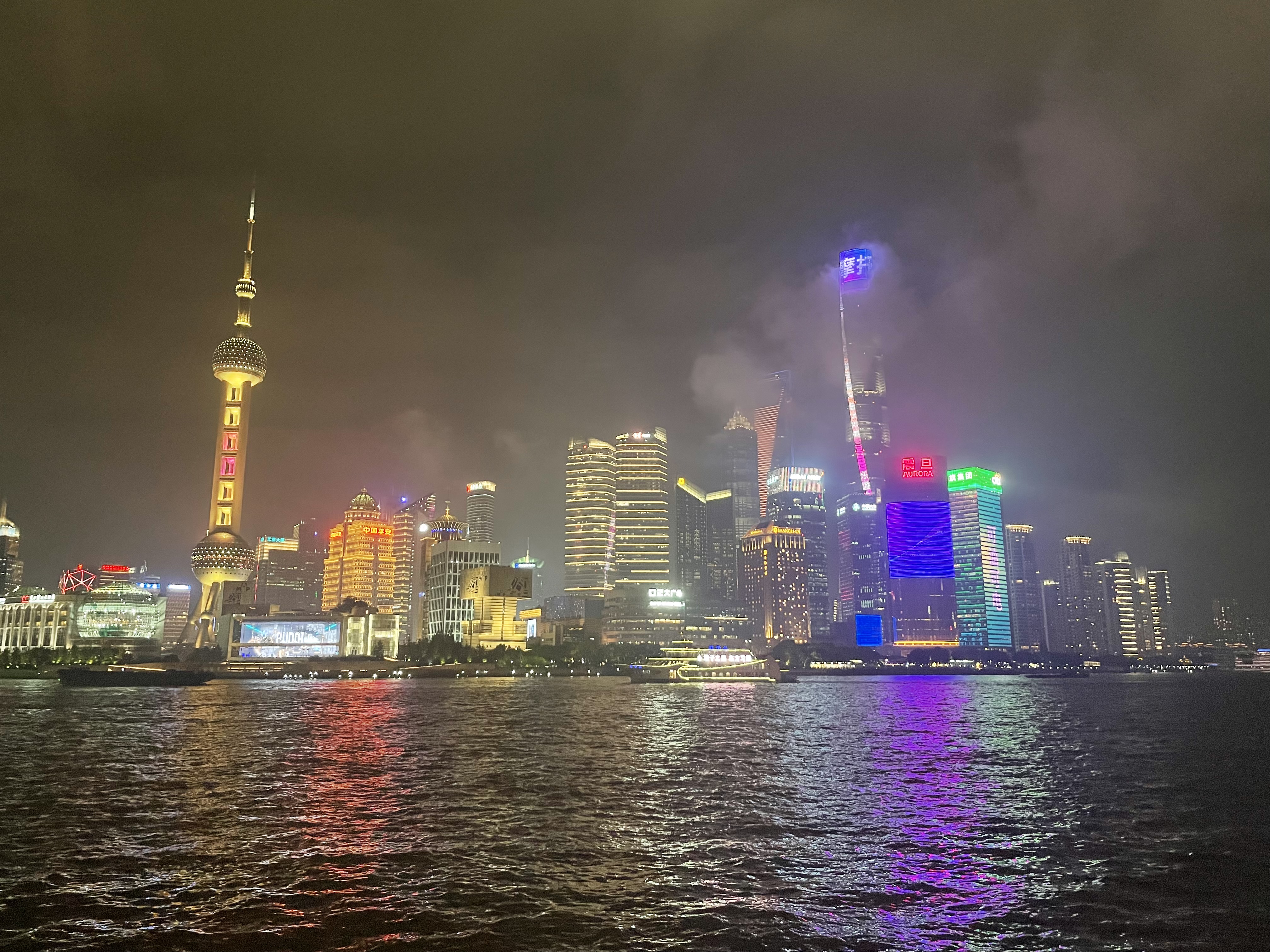 N&auml;chtliche Skyline von Shanghai mit beleuchteten Wolkenkratzern und reflektierenden Lichtern auf dem Fluss.